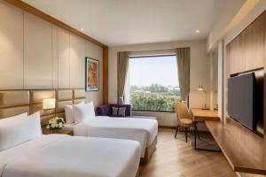 阿姆利则Ramada Encore by Wyndham Amritsar Airport的酒店客房设有两张床和一台平面电视。
