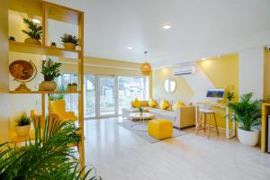 新德里Bloom Hotel - GK2的客厅配有黄色和白色家具和植物