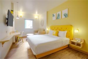新德里Bloom Hotel - GK2的一间卧室配有一张带黄色床头板的大床