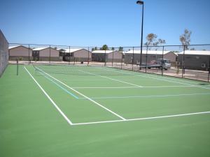 卡拉萨Aspen Karratha Village的一个网球场,有两个人在打