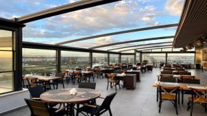 阿达纳Türkmen Riverside Hotel Adana的餐厅设有桌椅和大窗户。