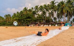 爱妮岛Mad Monkey Hostel Nacpan Beach的躺在沙滩上毛巾的女人