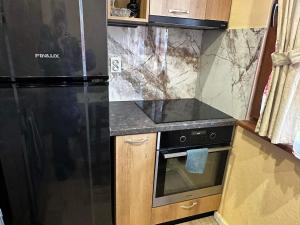 索非亚Апартамент Миели的厨房配有黑色冰箱和炉灶。