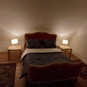 万泽内姆Les vignobles d'Alsace的一间卧室配有一张大床,桌子上放着两盏灯
