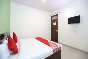Garhi HarsāruOYO Flagship 44151 Royal Guest House的一间卧室配有一张带红色枕头的床和电视。
