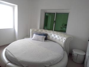BenguelaResidencial beira mar Benguela的白色卧室配有白色床和蓝色枕头