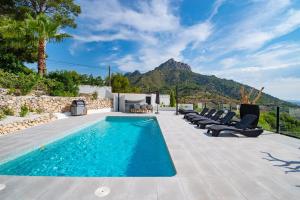 卡尔佩Calpeview II Luxury Villa By Calpitality的一个带椅子的游泳池,后方是一座山。