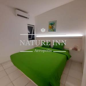 当格浪NATURE INN Aeropolis AR3的一间卧室配有一张绿色的床,上面有标志