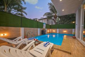 罗纳瓦拉Elegant Villa By Tropicana Stays的一个带白色躺椅的游泳池以及一间房屋