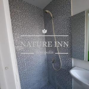 当格浪NATURE INN Aeropolis AR3的一间带淋浴的浴室,配有自然旅馆内的文字