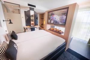 布雷达Gr8 Hotel Breda的一间卧室设有一张床、电视和屏幕上的足球播放机