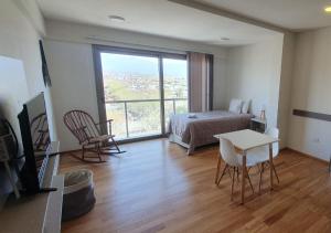 卢汉德库约Apart Hotel Quijote by DOT Suites的一间卧室配有一张床、一张桌子和一个窗户。