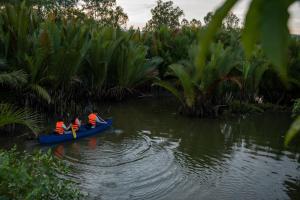 贡布Kampot Eco Village的三人乘着蓝色的独木舟在水面上