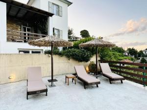 扎戈拉Luxury Villa at Pelion- Ruby的庭院里摆放着一组椅子和遮阳伞