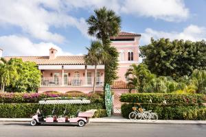棕榈滩克罗尼酒店的前面有高尔夫球车的粉红色房子