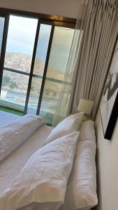 马斯喀特City Gem - Qurm的窗户客房内的一张带白色枕头的床