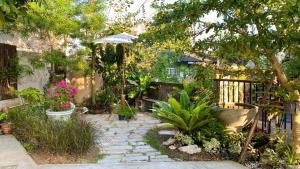 清莱Cozy place @ Chiangrai的花园设有种有植物和遮阳伞的石道