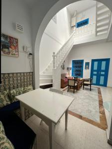 西迪·布·赛义德La maison 4 puits的客厅配有白色桌子和楼梯。