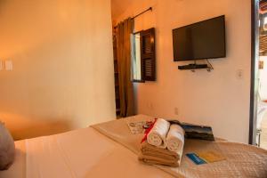卡诺格布拉达Pousada Vila Canoa的酒店客房配有带毛巾的床和平板电视。