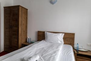 普雷代亚尔Vila Edelweiss的一张铺有白色床单的床和木制床头板