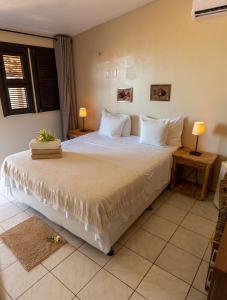 卡诺格布拉达Pousada Vila Canoa的卧室配有一张带白色床单和枕头的大床。