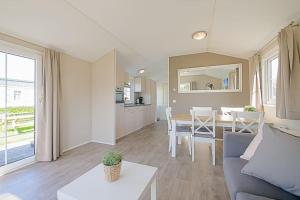 卡兰茨奥赫Chalet Luttikduin 22, met ruime tuin! - Callantsoog的带沙发的客厅和用餐室
