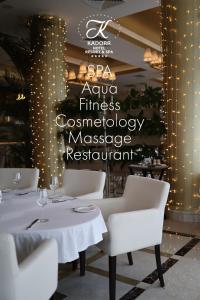 敖德萨卡多尔度假酒店的一间设有白色桌椅和标志的餐厅