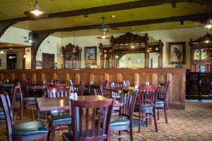 谢里登Sheridan Inn - Best Western Signature Collection的一间带木桌椅的餐厅和一间酒吧