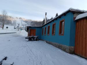 贝内茨科Little Trees Apartment的一座蓝色的建筑,有一辆汽车停在雪地里