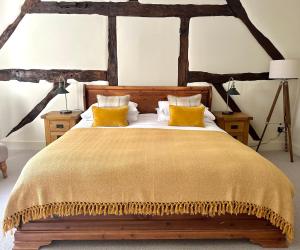 阿伯利The Manor at Abberley的一间卧室配有一张带黄色枕头的大型木制床。