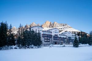 卡雷扎湖Grand Hotel Carezza Multiproprietà的雪覆盖的山前的建筑物