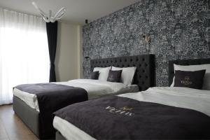 普里什蒂纳Vetus Hotel的酒店客房带两张床和一面墙