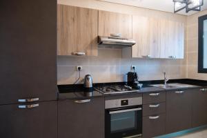 拉巴特Appartement luxueux Prestigia的厨房配有木制橱柜和炉灶烤箱。