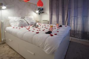 拉尼Thermal & Home cinéma Disneyland Paris and Terrasse的一张白色的床,上面有红玫瑰和蜡烛