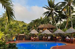 阿鲁坦加Etu Moana Boutique Beach Villas - Adults Only的度假村的游泳池,有人坐在桌子旁
