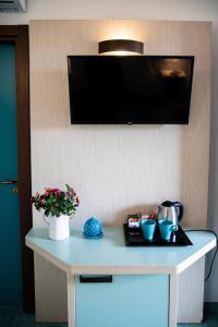 滨海波利尼亚诺皮埃特拉布鲁Spa度假酒店 - CDS酒店的花卉墙上的桌子和电视机