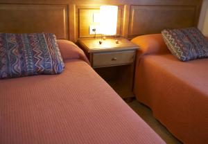 圣洛伦索-德莫鲁尼斯Casa Rural Rebost的客房设有两张床和一张带台灯的桌子。