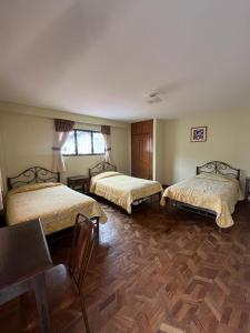 拉巴斯The Hidden House Hostel的一间卧室设有两张床,铺有木地板