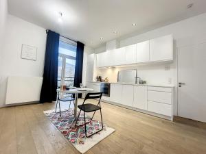 布鲁塞尔Cosy Apartment Brussels - Cinquantenaire的厨房配有白色橱柜和桌椅