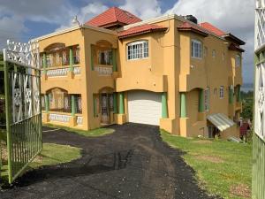 蒙特哥贝POINCIANA APARTMENT ONE 257 POINCIANA DRIVE GREEN WOOD MONTEGO BAY JAMAICA的一座黄色的大房子,前面有一个门