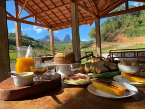 佩德拉阿祖尔Pousada Rural Recanto do Lago的餐桌,早餐包括面包和橙汁