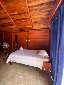 福尔图纳Cabañas SyC的木制客房内的一间卧室,配有一张床