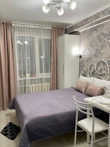 比什凯克Уютная комната-студия в центре Бишкека的一间卧室配有紫色的床和桌椅