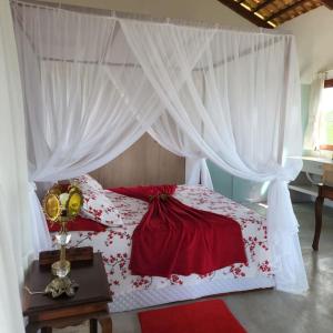 蒙蒂达斯加梅莱拉斯Chalé romântico, com vista panorâmica, para Casais的卧室配有红色和白色的床和窗帘