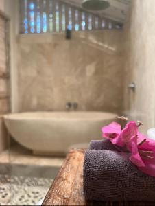 吉利阿尔吉利埃尔椰子旅舍的浴室里的一条毛巾,上面有一张桌子上的一个粉红色的弓