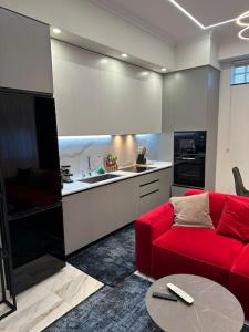 都拉斯Skyen Luxury Apartments的一间带红色沙发的客厅和一间厨房