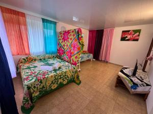 土布艾岛Toamanahere Guesthouse的一间带椅子和一张带彩色窗帘的床的房间