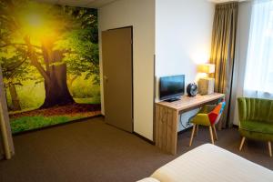 登海尔德森林酒店的酒店客房设有一张书桌、一台电视和一幅木壁画