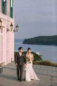 富国Labe Hotel Phú Quốc - Sunset Town - Địa Trung Hải的一位新娘和新郎在大楼前行走