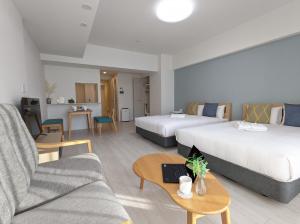 大阪ESLEAD HOTEL Osaka Tsuruhashi的酒店客房,设有两张床和一张沙发